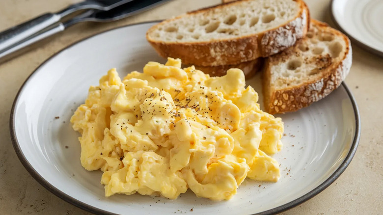Seasoned scrambled eggs and toast on a plate