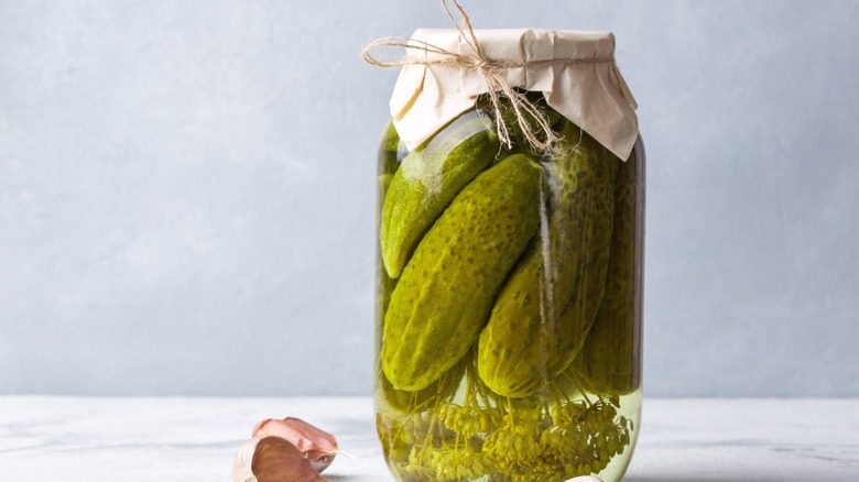 Cucumbers fermenting in a jar with dill and garlic, in the process of becoming pickles.