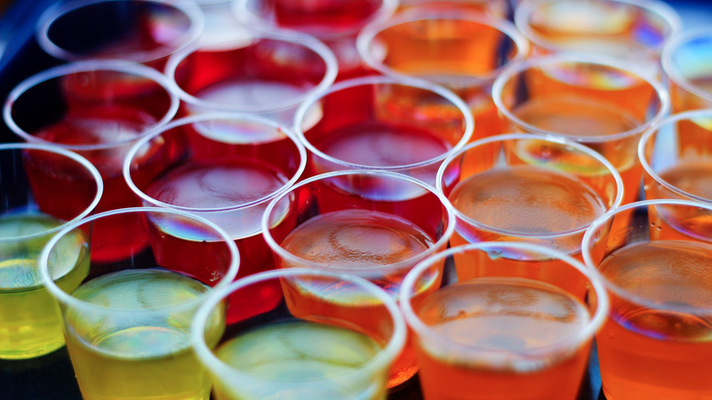 Yellow, orange and red Jell-O shots in clear plastic shot glasses.