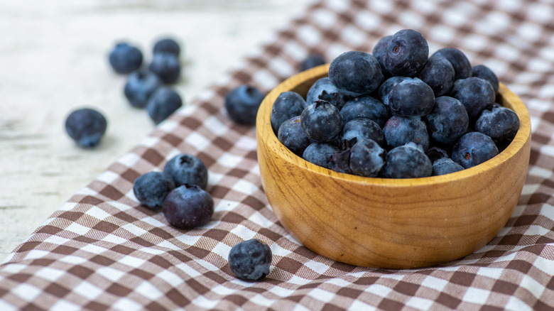Blueberries in wood bowl on brown gingham