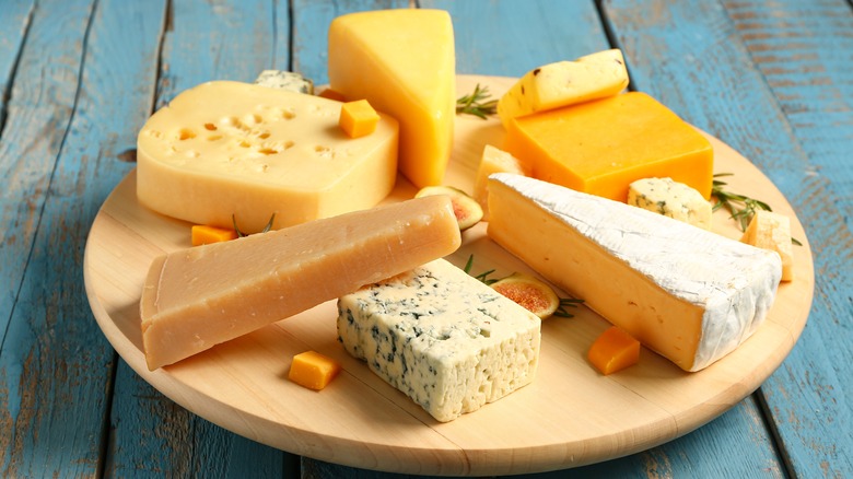 a variety of cheeses on wooden board