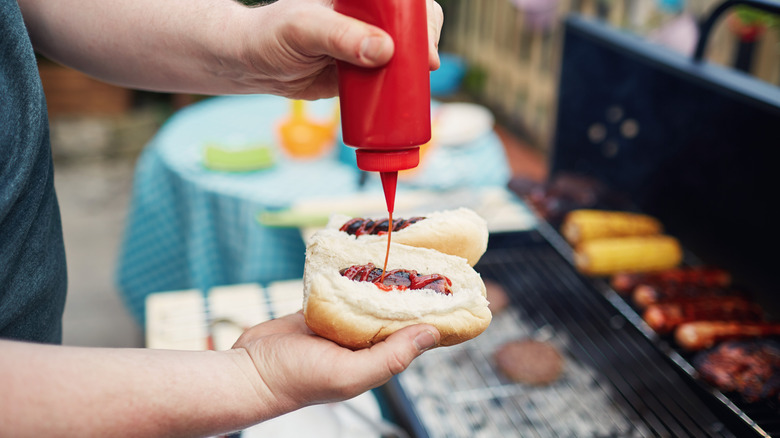 putting ketchup on hotdog at outdoor BBQ
