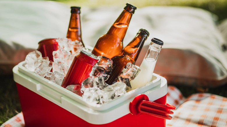 A red ice cooler full of canned and bottled drinks
