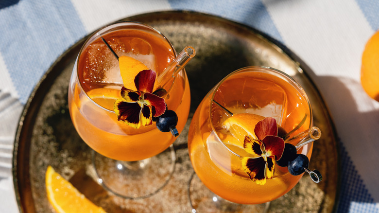 Two orange summery cocktails in wine glasses on a tray