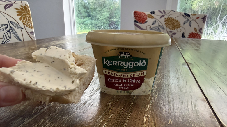 Kerrygold onion & chive cream cheese on a bagel with container in background