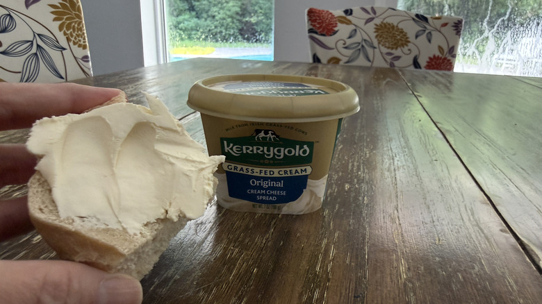 Kerrygold original cream cheese on a bagel with container in background