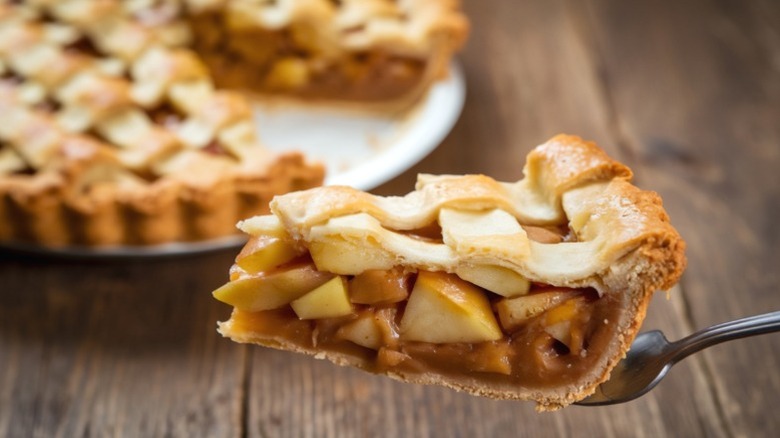 A slice of apple pie being separated from the whole.
