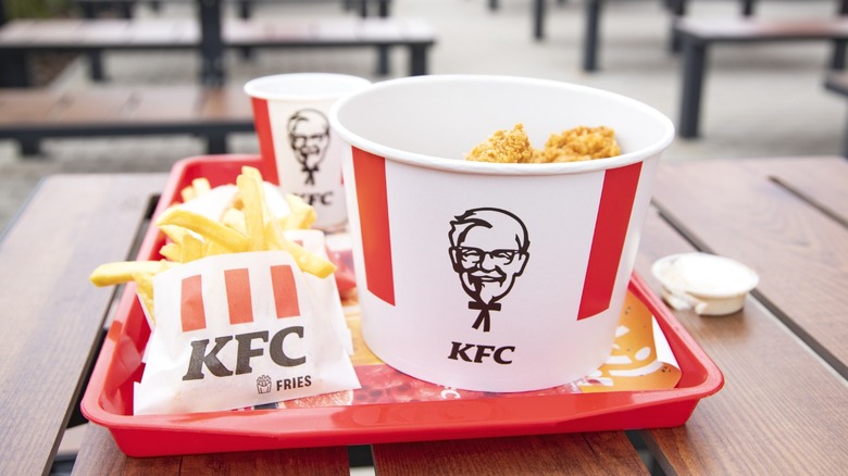 A KFC meal with a bucket of chicken and french fries.