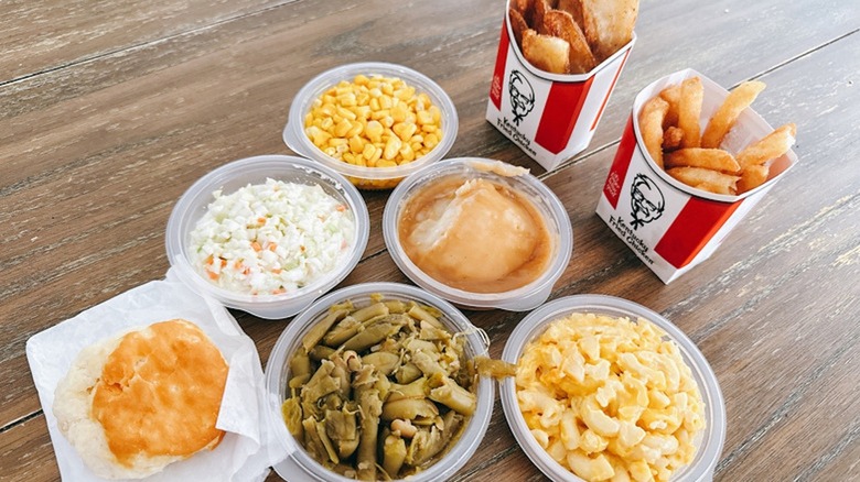 Assorted side dishes from KFC including corn, coleslaw, mashed potatoes, fries, mac and cheese, green beans, and a biscuit