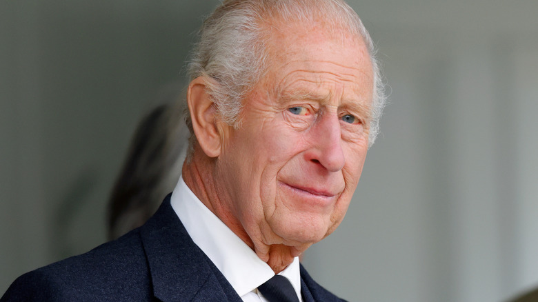 King Charles smiles in a dark suit at an event