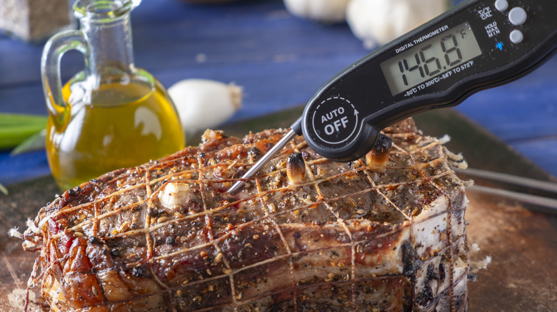 A digital thermometer being used to probe a piece of meat