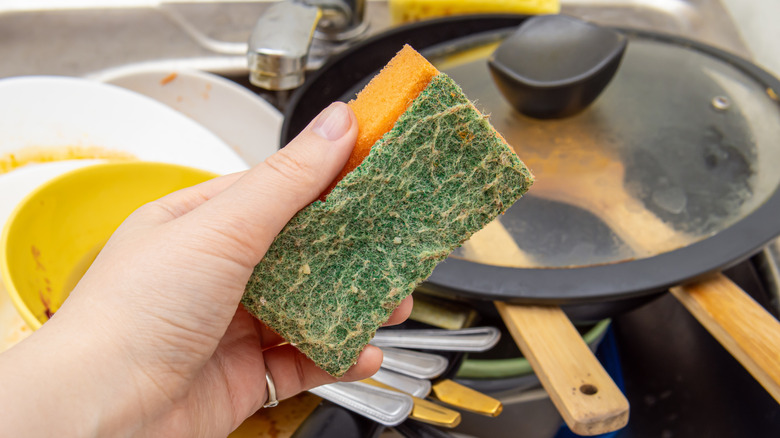 Person washing dishes with a kitchen sponge