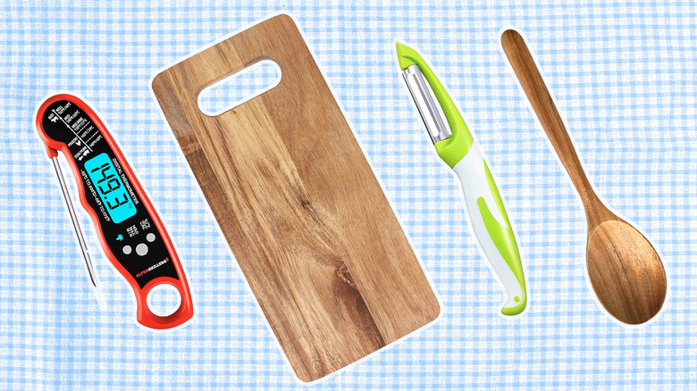 A selection of kitchen tools including a meat thermometer, cutting board, peeler, and wooden spoon