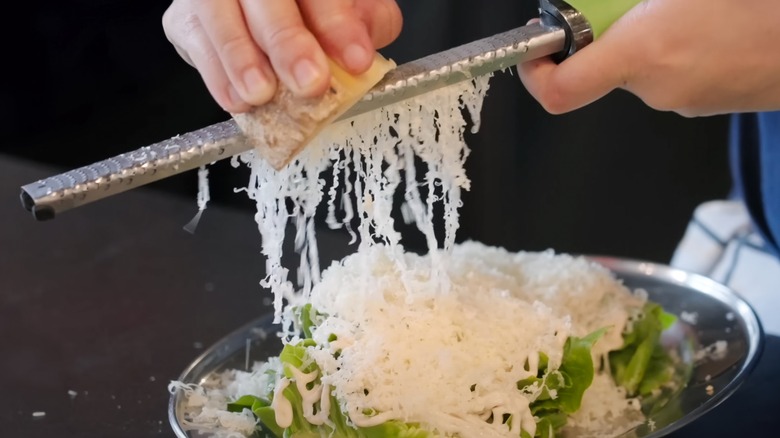 Person using a microplane grater to grate cheese