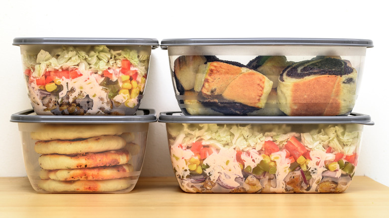 Four plastic food storage containers filled with food