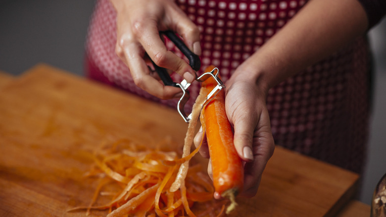 Woman peeling a carrot with a vegetable peeler