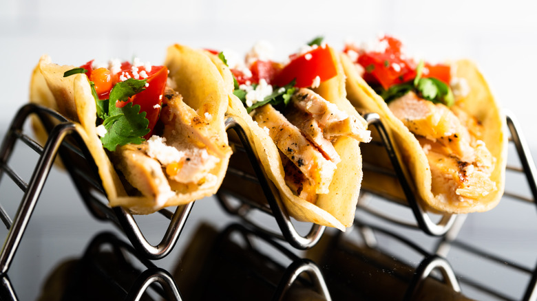 A metal taco rack holding three tacos