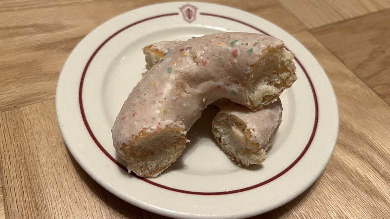 a Krispy Kreme's Fruity Pebbles Milk Original Glazed Doughnut cut imnm half