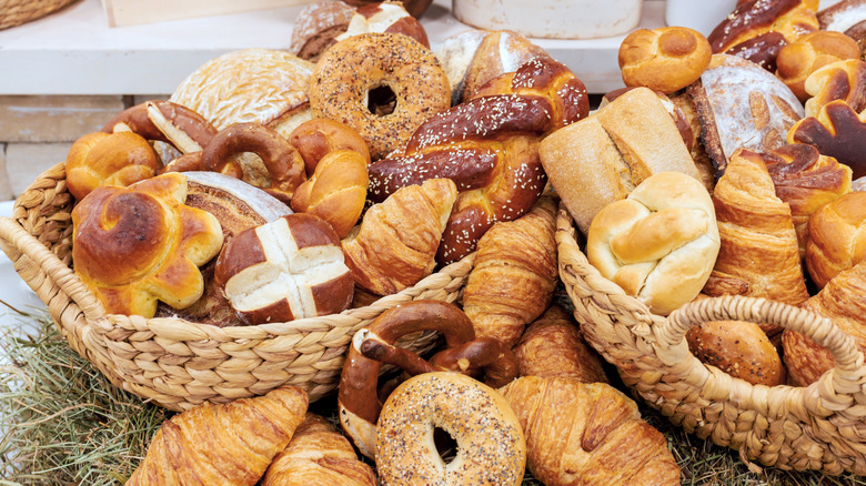 Baskets overflowing with different kinds of bread in a bakery setting.