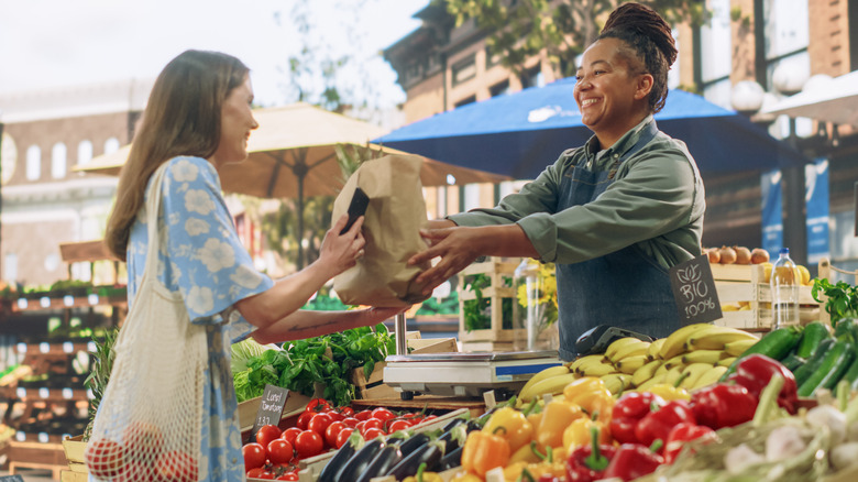 A woman buys produce at a farmer's market stand