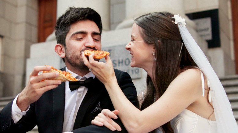 Newlywed man and wife smiling and eating pizza