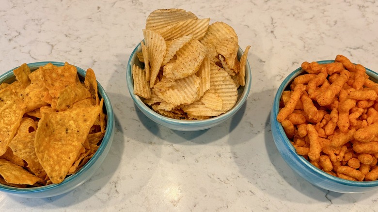 A close-up of Lay's Flavor Swap Doritos, Ruffles, and Cheetos in bowls on countertop