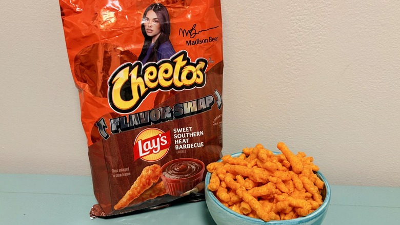 A bag and bowl filled with Sweet Southern Heat Barbecue Cheetos Flavor Swap, with photo of influencer Madison Beer above Cheetos logo on bag