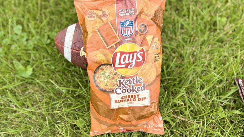 A bag of Lay's kettle cooked cheesy buffalo dip flavor potato chips in a field