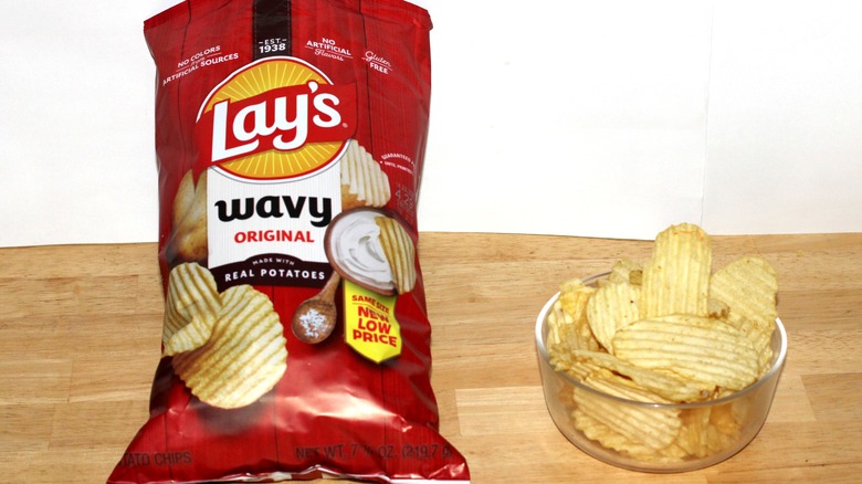Chips in bowl next to bag of Lay's Wavy Original potato chips