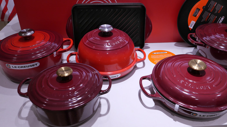 A table full of various Le Creuset cookware on display.