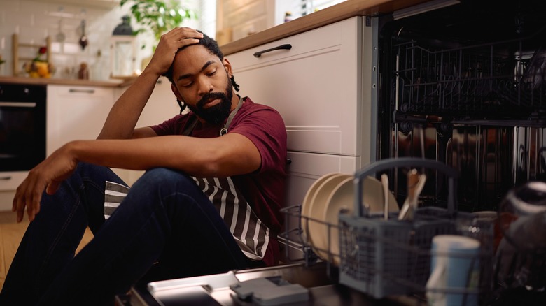 Distraught person staring at open dishwasher