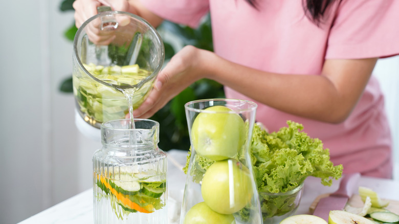 A young woman preparing some cucumber citrus water