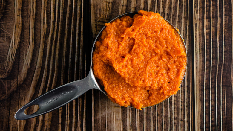 A measuring cup full of pumpkin puree.