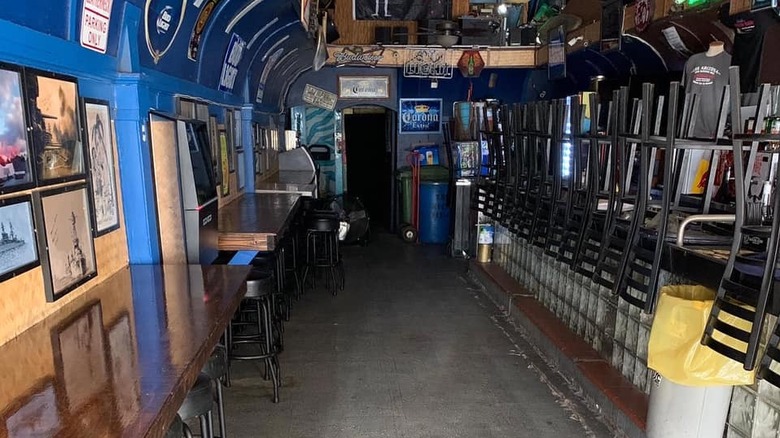 Chairs stacked on top of the bar in a narrow room with blue walls