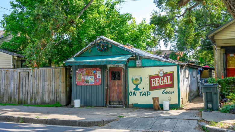 Narrow turquoise building with a wreath above the door and a Regal beer mural painted on the wall.