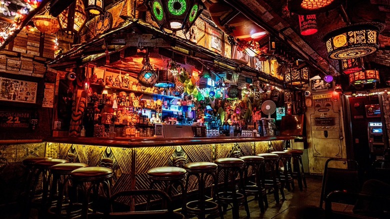 Eleven stools lined up at a tiki themed bar