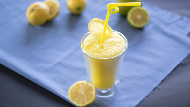 A lemon slushie with lemon slices and a yellow bendy straw