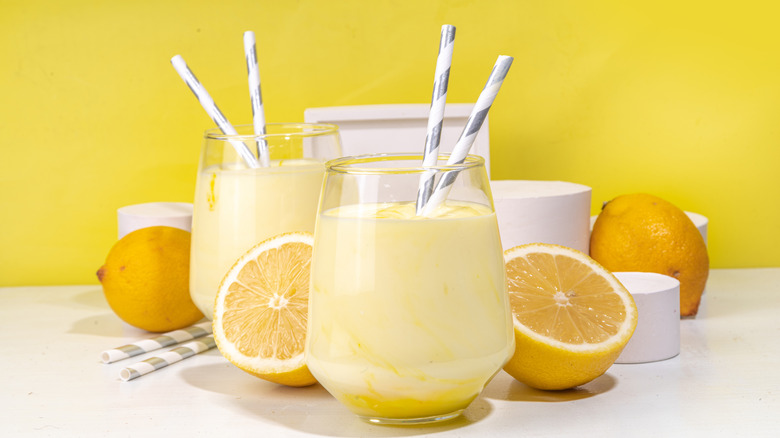 Several creamy lemon slushies with silver spiral straws and sliced lemons