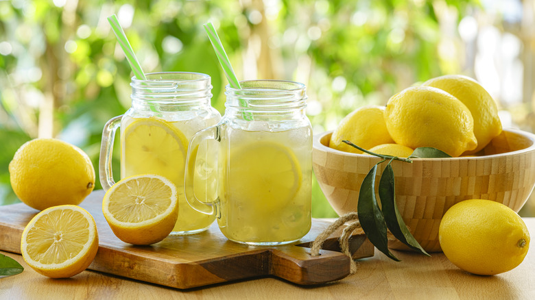 Lemonade in mason jars and lemons sitting on a table outside