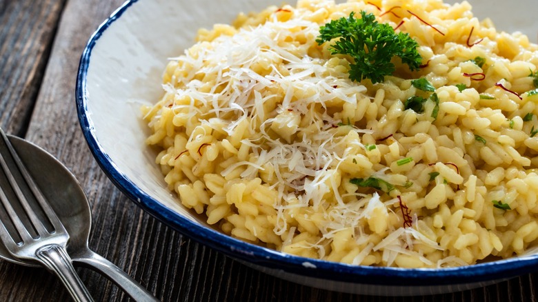 Risotto with cheese in bowl on wood table up close