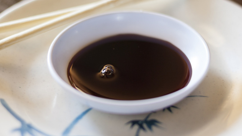 Bowl of soy sauce with chopsticks on table