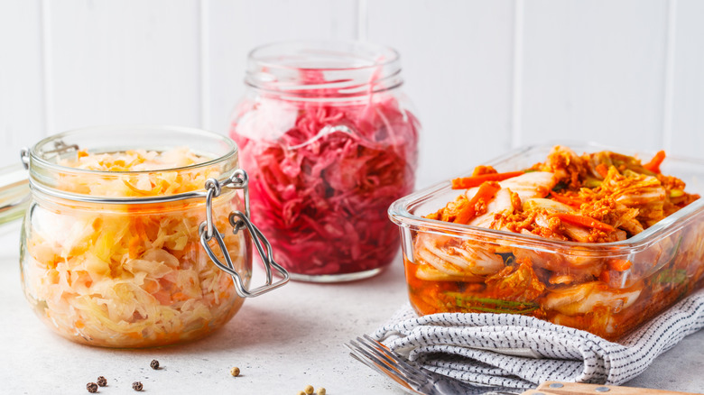 Korean kimchi cabbage, beet sauerkraut and sauerkraut in glass jars, white background. Probiotics food concept.