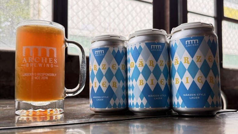 A beer in an Arches Brewing glass, beside a six pack of Marzen-style lager