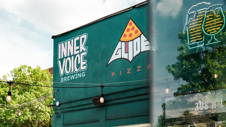 A green building with Inner Voice Brewing and Glide Pizza painted signs