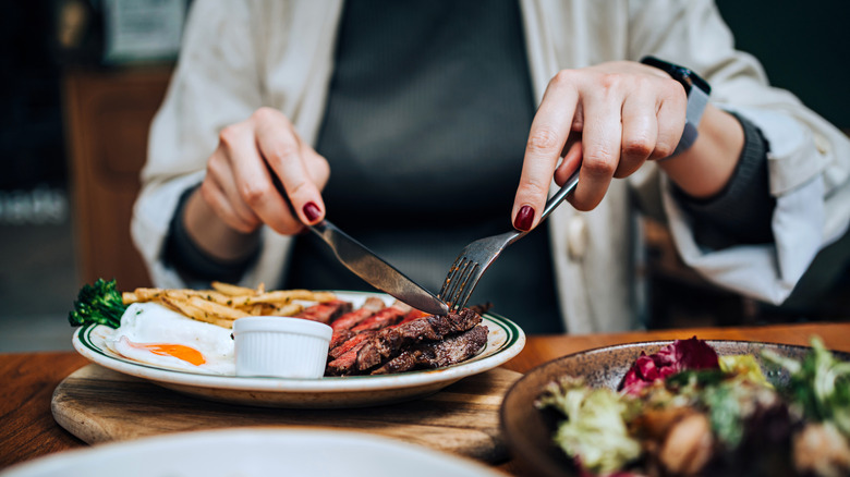 Woman eating steak at a restaurant