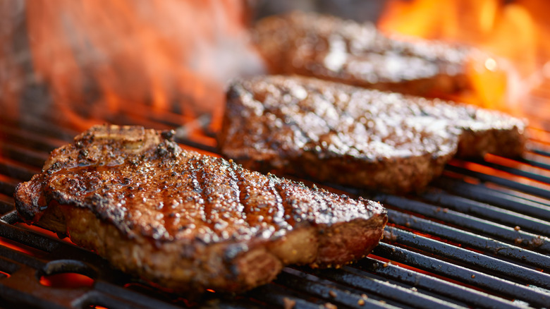 Steaks grilling over an open flame