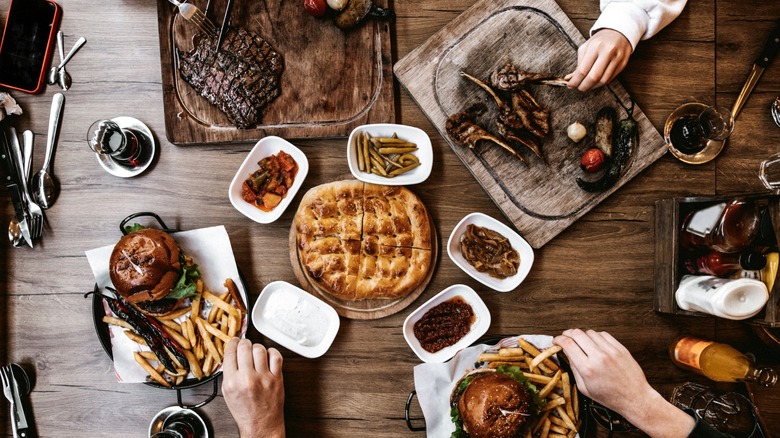 Top view of people eating in restaurant with burgers, fries, and steaks on table