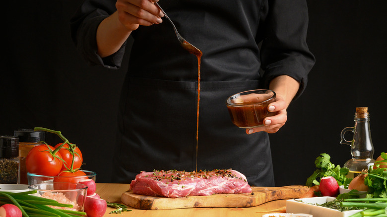 Chef drizzling marinade on steak