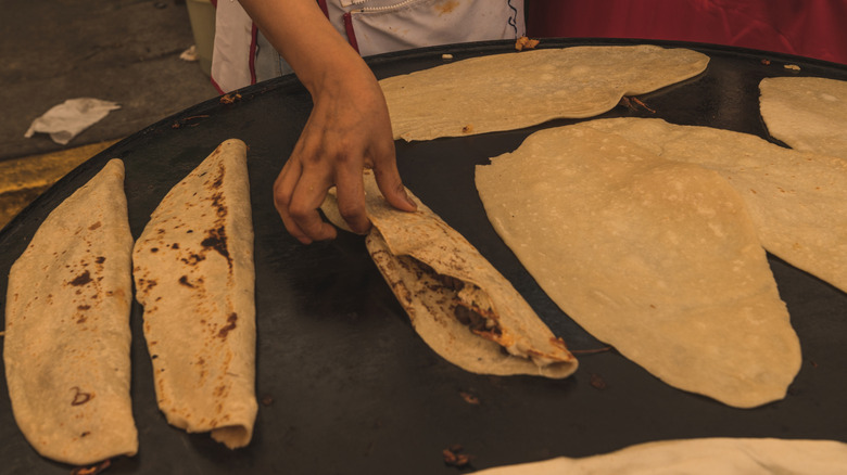 Someone cooking multiple machete quesadillas on a large stove