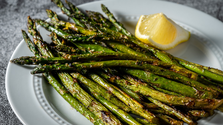 Crispy grilled asparagus spears on a plate with a side of lemon